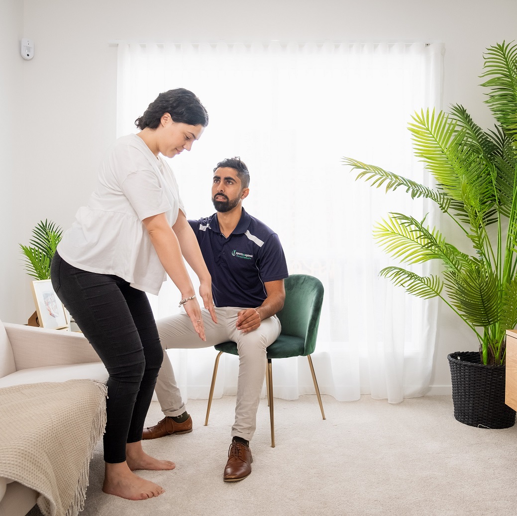 Physiotherapist and patient being pictured, the physiotherapist is guiding the patient to stand up,