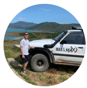 Max, TRS Client smiling with sunglasses on. Sun is shining and the beach is in the background. 